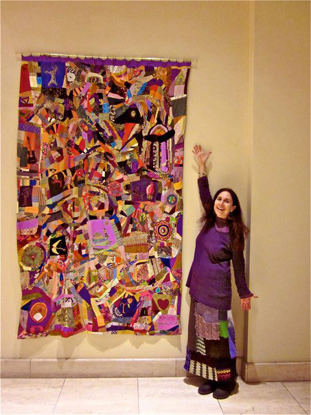 Patchwork wall hanging made by Alicia Bay Laurel.  In an exhibition.  Alicia Bay Laurel next to wallhanging.